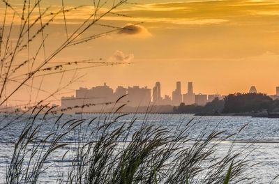Scenic view of sea and buildings against sky during sunset