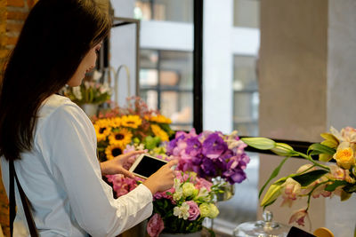 Young woman photographing flower bouquets in store
