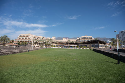 Buildings on field against blue sky