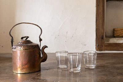 Close-up of antique tea kettle and glasses on floor at home
