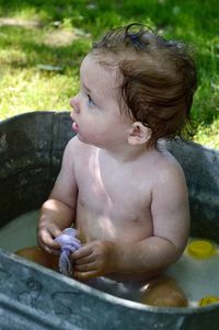 Cute shirtless baby girl sitting in bathtub