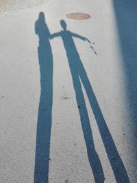 Shadow of man and woman standing on road