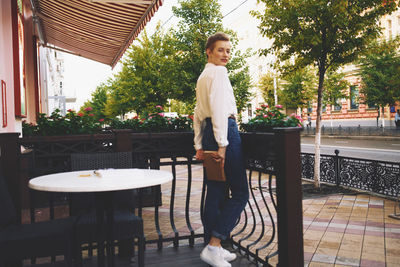 Portrait of young woman standing on table against trees