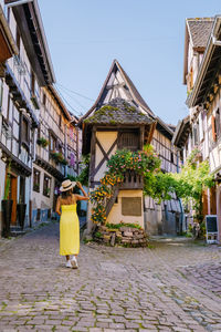 Rear view of woman walking on street amidst buildings