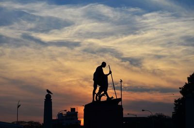 Low angle view of silhouette mahatma gandhi statue against sky during sunset