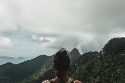 Rear view of woman standing on mountain against sky