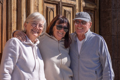 Portrait of smiling friends standing against wall