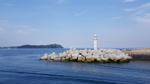 Lighthouse by sea against sky