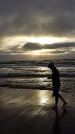 Man standing on beach against sky during sunset