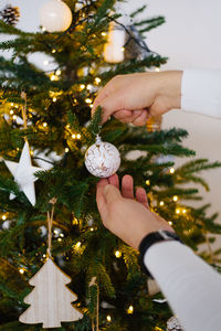 A man decorates a christmas tree, hangs a ball on a christmas tree. close-up of hands