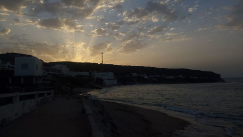 Scenic view of beach against sky at sunset
