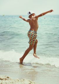 Rear view of shirtless boy jumping in sea during sunny day