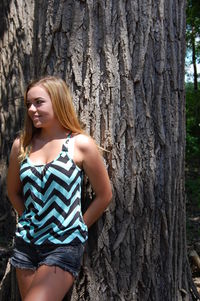 Young woman leaning on tree trunk