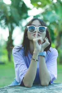 Portrait of young woman wearing sunglasses sitting outdoors