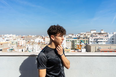 Full length of young man standing against blue sky