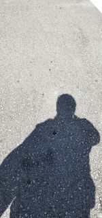 Shadow of person on road during sunny day