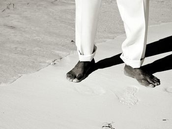 Low section of man standing on shore at beach