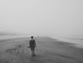 Rear view of man on beach against sky