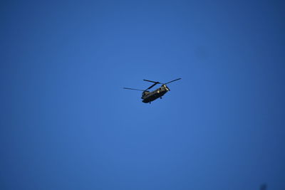 Low angle view of airplane flying against clear blue sky
