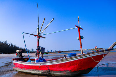 Fishing boats moored on sea against clear blue sky