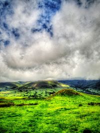 Scenic view of grassy field against cloudy sky