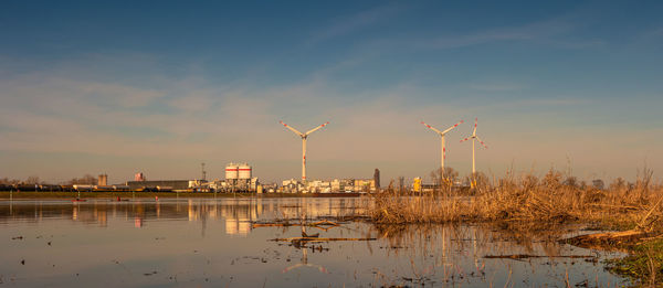 Cranes in factory against sky