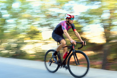 Rear view of man riding bicycle on road