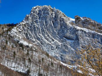 Low angle view of snowcapped mountain against blue sky