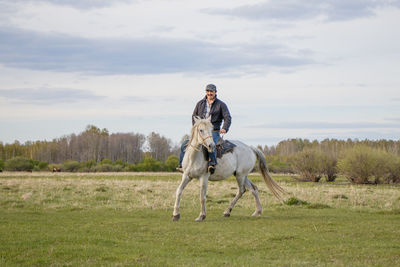 A fermer on a white horse in the field