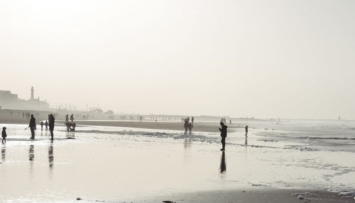 People on beach against clear sky