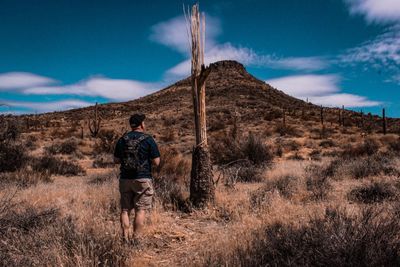 Rear view of man standing on field against sky