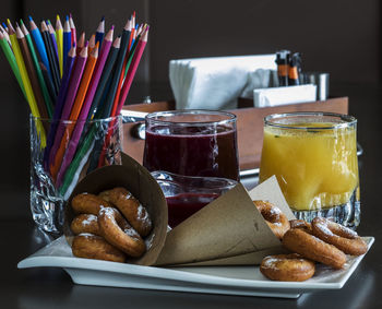 Close-up of food and drink by colored pencils in tray on table