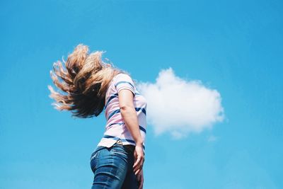 Low angle view of woman standing against blue sky