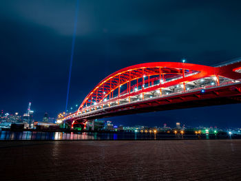 Illuminated bridge over river at night