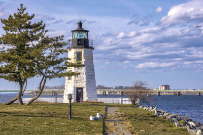 Lighthouse by sea against sky