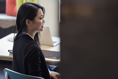 Side view of businesswoman sitting at table in creative office