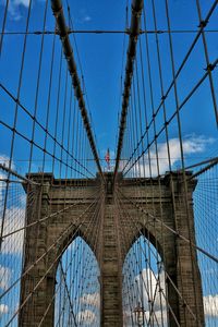 Low angle view of suspension bridge against blue sky