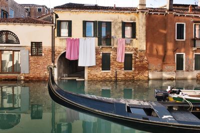 Boats moored in canal by buildings in city