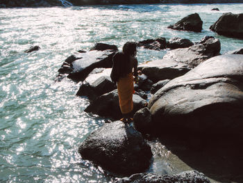 Rear view of man on rock in sea