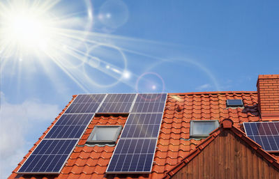 Low angle view of bright sun over building against sky