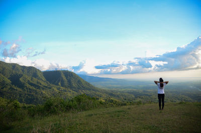 Rear view of man standing on landscape against sky