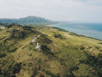 Scenic view of sea by green landscape against sky