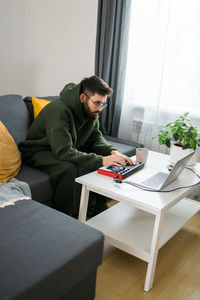 Young woman using laptop while sitting on chair at home