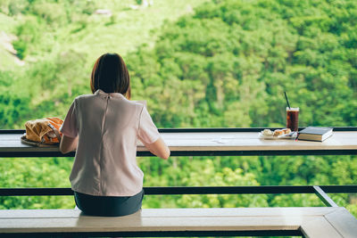 Rear view of woman sitting on table