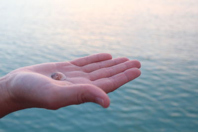 Close-up of hand against sea