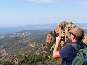 Hiker photographing mountains from camera against sky