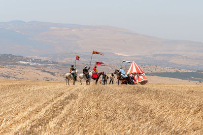 People riding motorcycle on field against sky