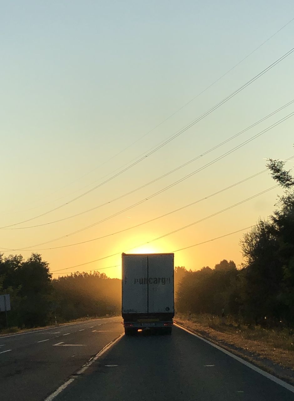 CAR ON ROAD AGAINST SKY AT SUNSET