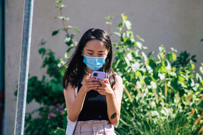 Young man photographing with mobile phone standing outdoors