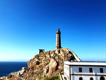 Low angle view of lighthouse by building against clear blue sky